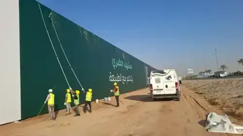 فريق عمل أفضل شركة تنظيف واجهات محلات بالرياض يقوم بتلميع واجهة معرض تجاري كبير باستخدام أدوات تنظيف الزجاج الاحترافية