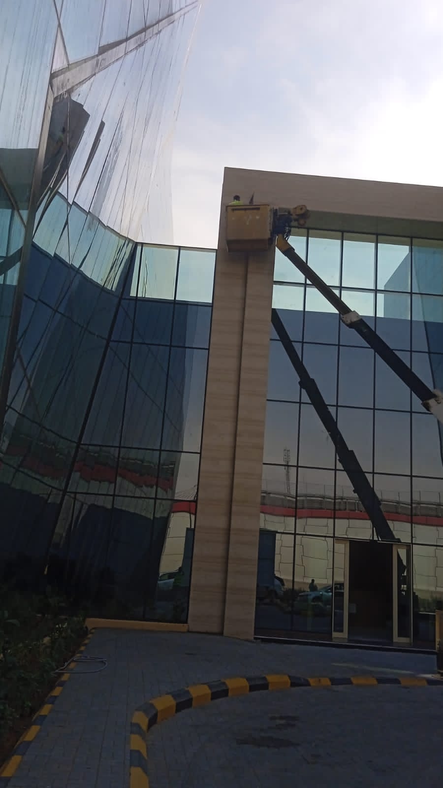 فريق شركة الجواد يقوم بتنظيف واجهة مبنى تجاري في حي الفلاح بالرياض باستخدام الرافعات.