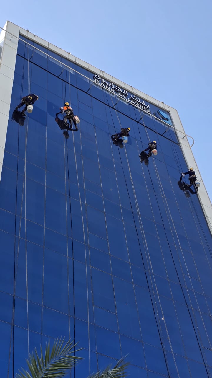 تنظيف واجهة برج زجاجي في حي الملقا بالرياض بواسطة فنيي شركة الجواد المعلقين بالحبال