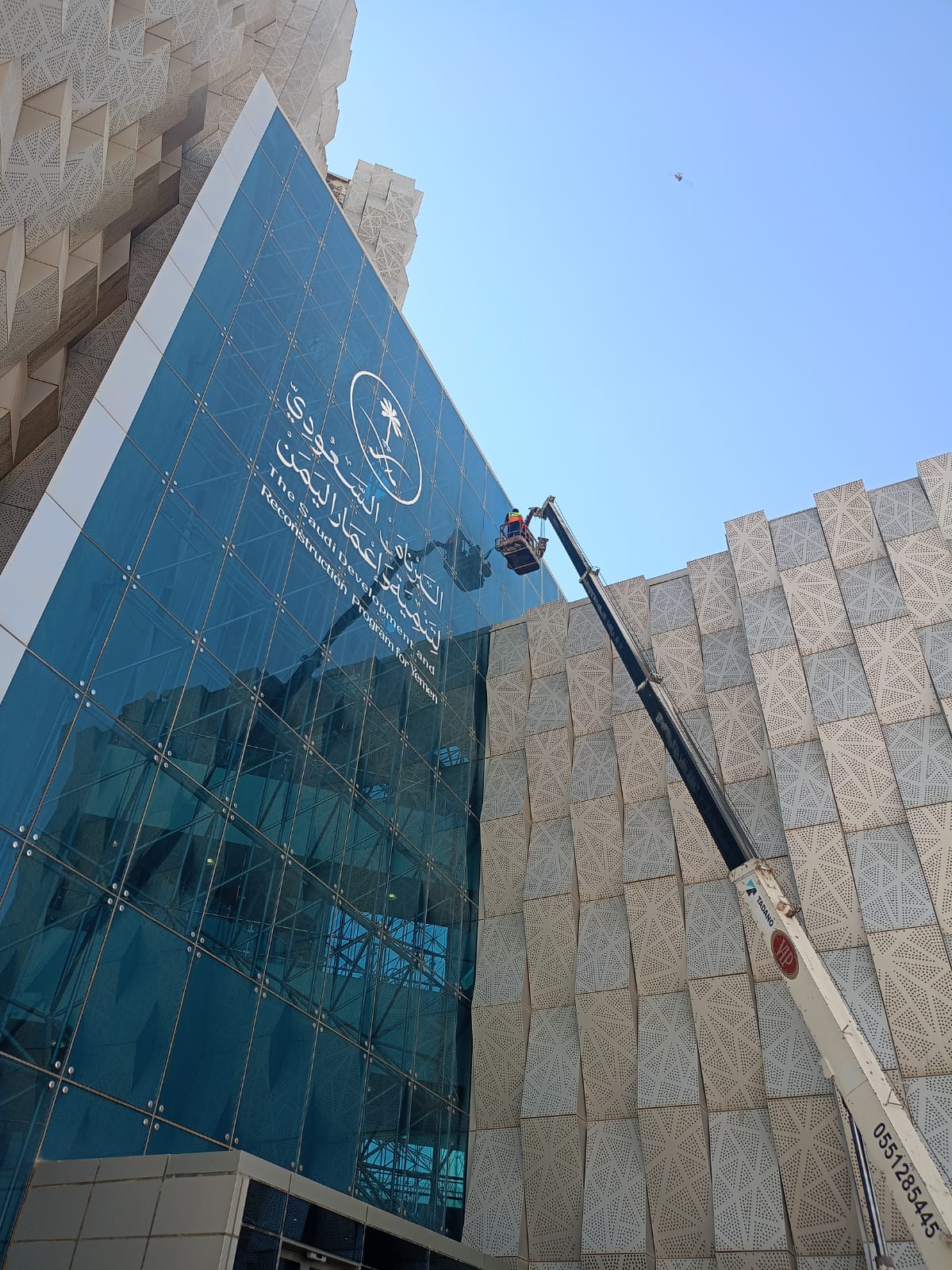فريق شركة الجواد يقوم بتنظيف وتلميع الواجهة الزجاجية لمقر البرنامج السعودي لتنمية وإعمار اليمن بالرياض