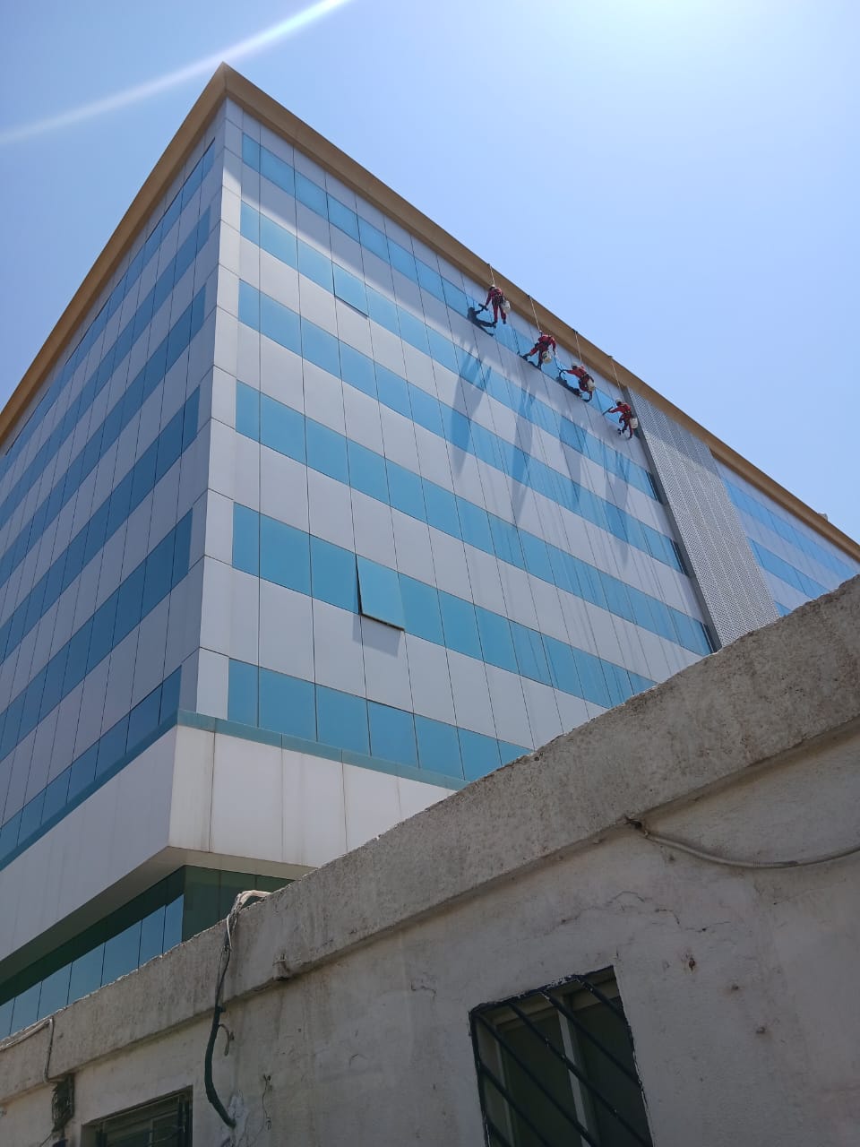 فريق شركة الجواد يستخدم الرافعات المخصصة لتنظيف الواجهات الزجاجية والكلادينج لمبنى في حي الملز بالرياض