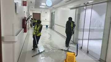 فريق متخصص من شركة الجواد يرتدي الزي الوقائي الكامل ويستخدم أجهزة الضباب البارد لتعقيم وتطهير غرف الانتظار في مستشفى بالرياض لضمان المطابقة المعيارية